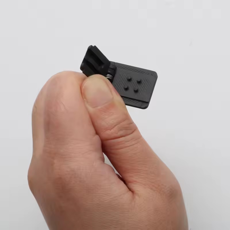 Detail malého černého upínacího dílu držáku DJI Mic 1 v ruce.